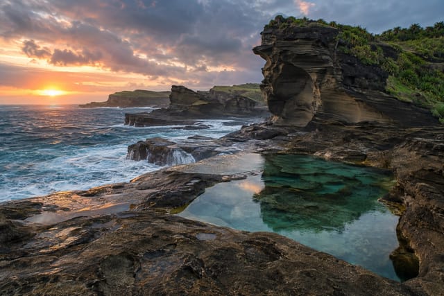 Illustration of dark sandstone rock formations and tidal pools beside foaming Pacific water in Biri, Northern Samar