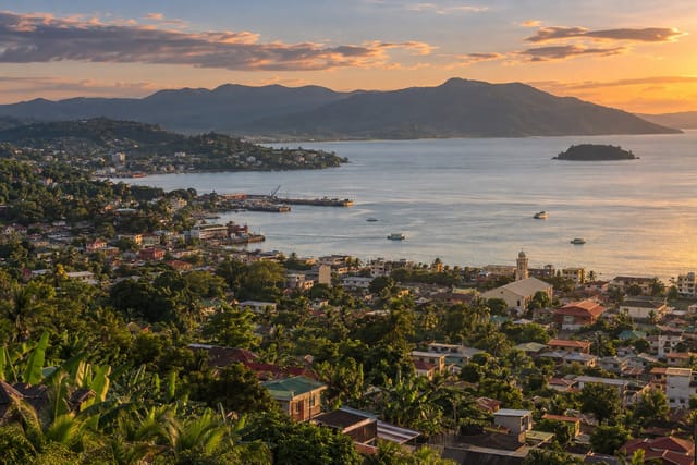 Illustration of a hilly city descending to a bay with small boats and green ridges in Pagadian